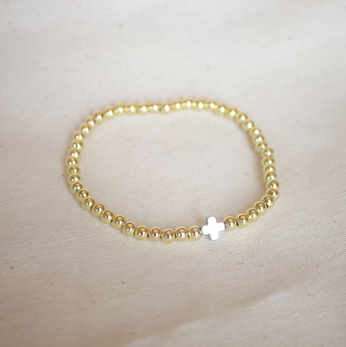 Pulsera dorada con cruz plateada