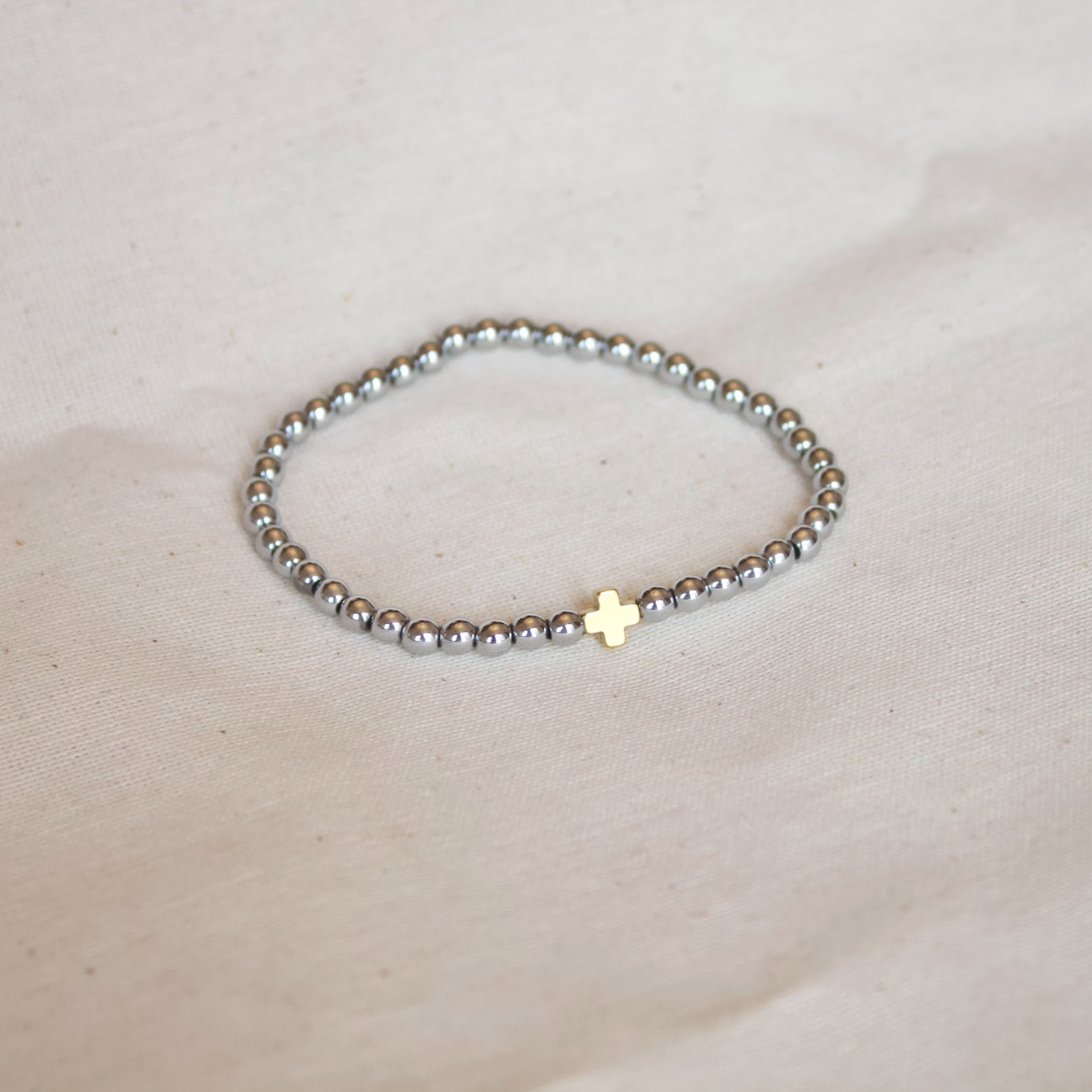Pulsera plateada con cruz dorada
